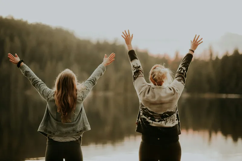 Two women salutation at a lake stock photo